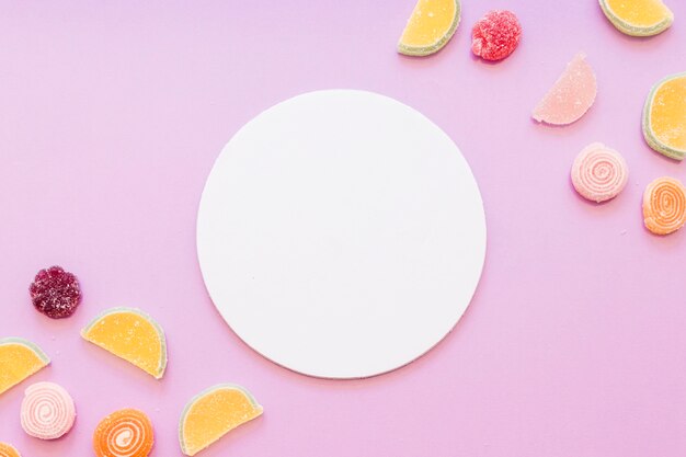 Белая круглая пустая рамка с желе конфеты на розовом фоне