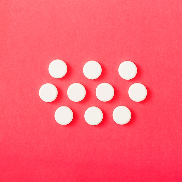 White circular pills over the red backdrop