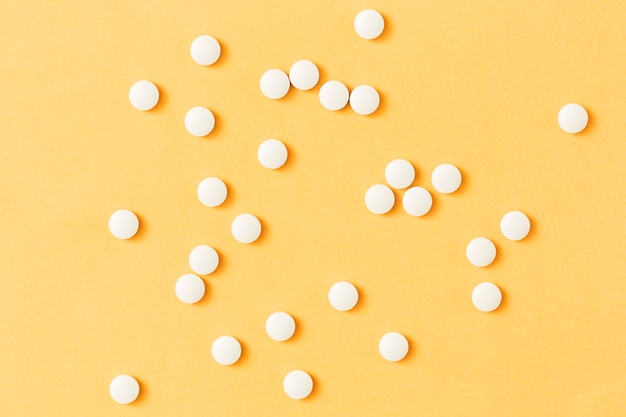 White circular pills over the yellow background