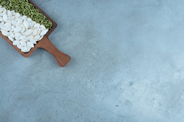 White and cleaned green pumpkin seeds on a wooden platter. High quality photo