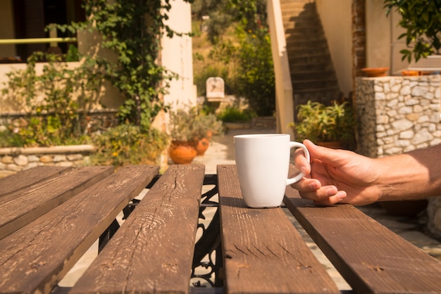 Tazza di caffè bianca sul tavolo con l'impostazione esterna