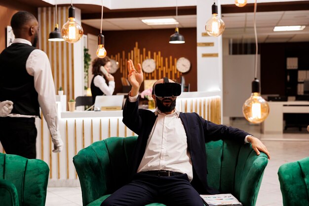 White collar worker uses vr glasses in lounge area at hotel, working on business project development before attending meeting. Entrepreneur with virtual reality headset on business trip.