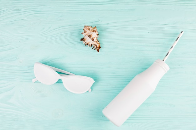 White colored sunglasses near bottle with straw 