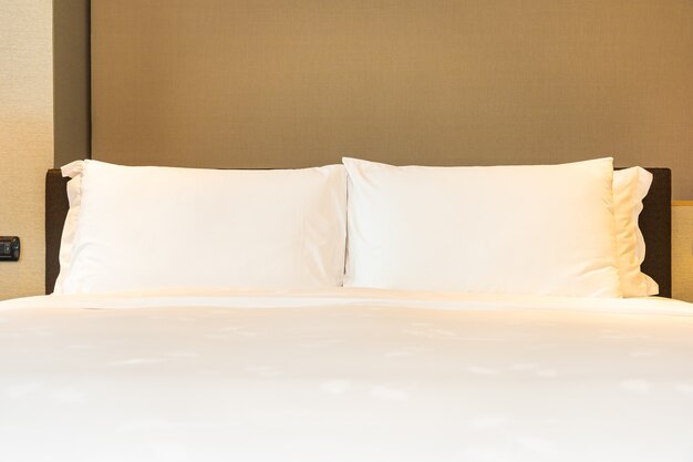 Белая удобная подушка и одеяло на кровати с легкой лампой