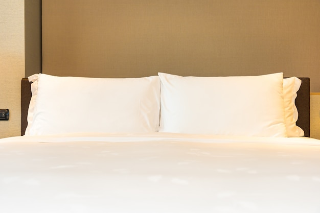 Белая удобная подушка и одеяло на кровати с легкой лампой