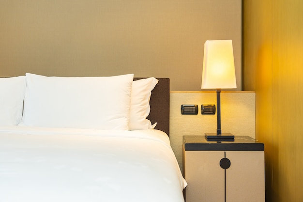 白い快適な枕と光ランプが付いているベッドの毛布