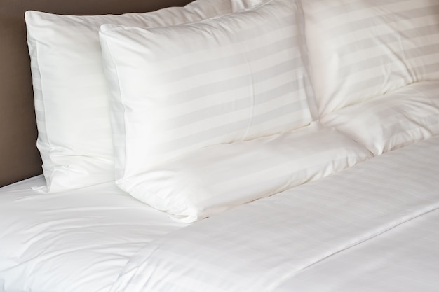 White comfortable pillows on bed with blanket