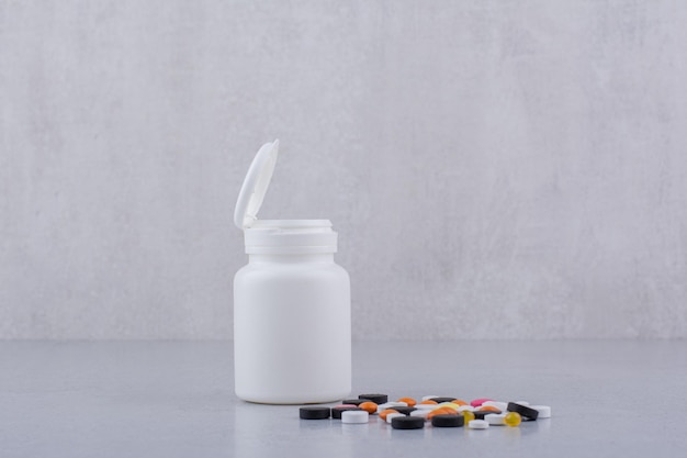 White container and bunch of various pills on marble surface. High quality photo