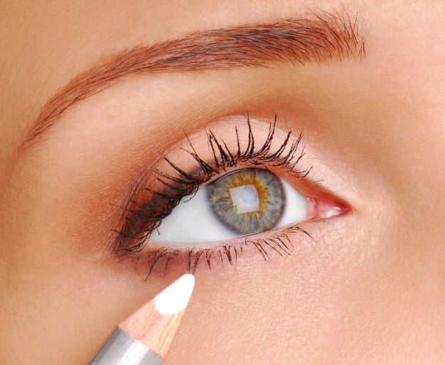 White Cosmetic pencil. Make-up tool. Womun eye is close-up.