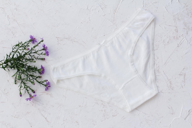 흰색 구조화된 배경에 꽃이 있는 흰색 면 팬티. 여성 속옷 세트입니다. 평면도.