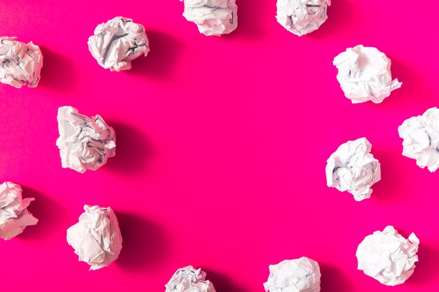 White crumpled paper ball on pink background