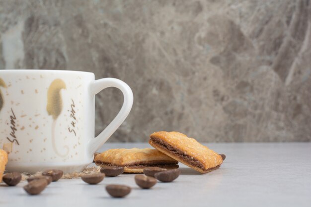 Белая чашка кофе с крекерами и кофейными зернами на белом фоне. Фото высокого качества