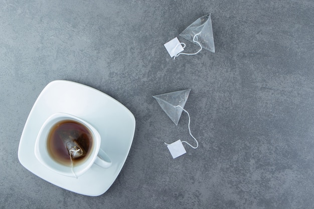 Foto gratuita una tazza bianca di tè caldo con bustine di tè.