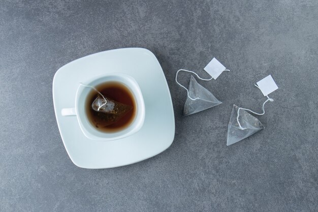 A white cup of hot tea with teabags .