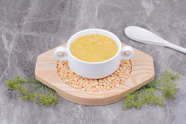 Free photo a white cup of pea beans soup on a wooden platter