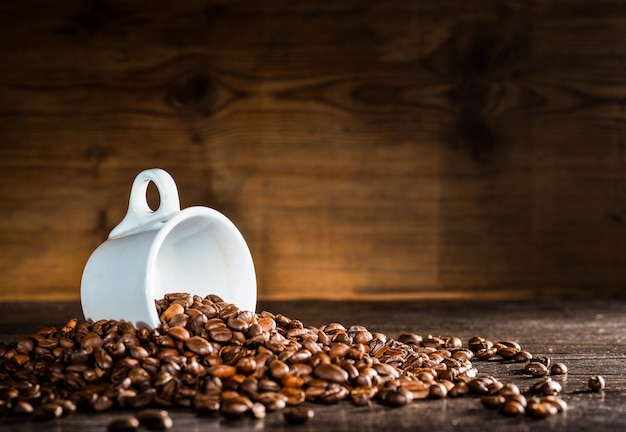 White cup surrounded by coffee beans