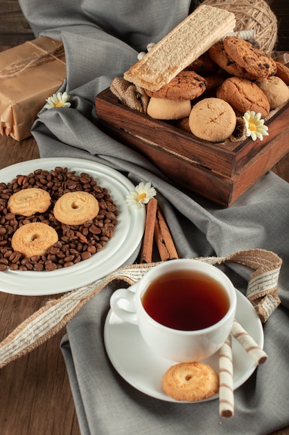 A white cup of tea with oatmeal cookies and biscuits