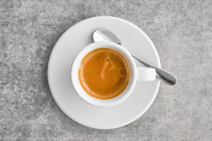 Free Photo white cup with fragrant strong espresso coffee with thick foam in a traditional greek coffee shop top view of coffee with saucer on gray marble table idea for background or poster