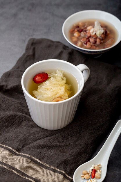 White cup with tea and a bowl with soup on a grey cloth