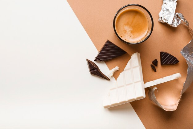 White and dark chocolate bar with coffee glass on dual background