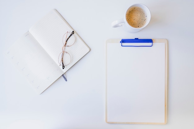 White desk with clipboard, glasses and coffee