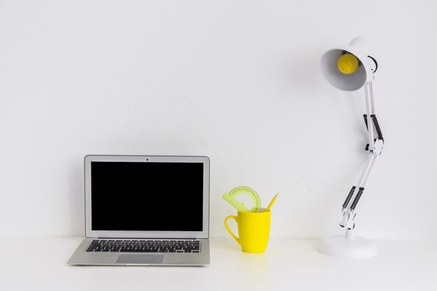 White desk with laptop and reading lamp