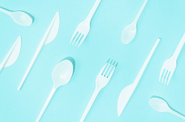 White disposable cutlery composition on turquoise background