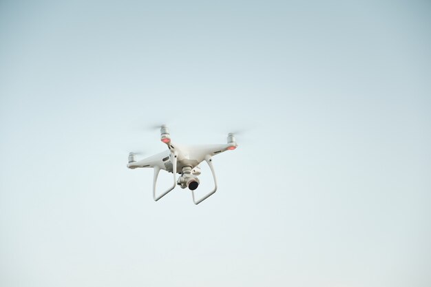 White drone hovering in a bright blue sky