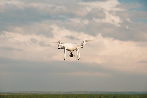 White drone hovering in a bright blue sky