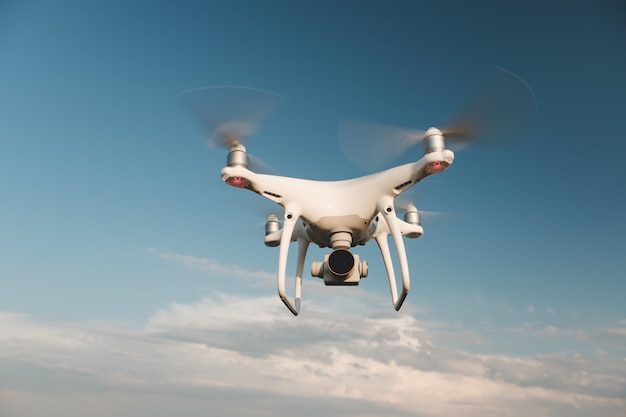 White drone hovering in a bright blue sky