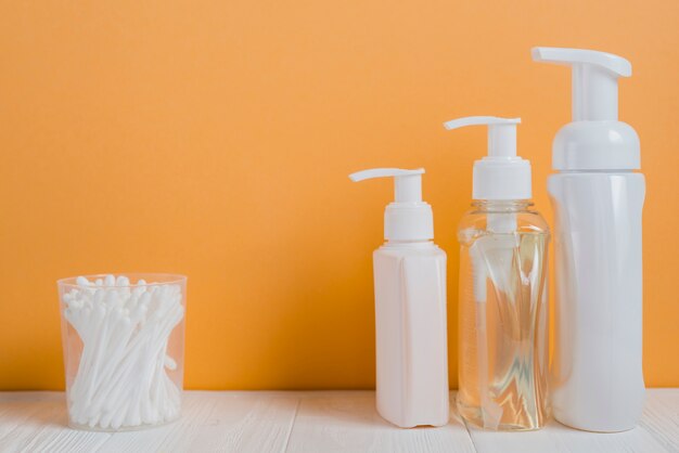 White ear buds with soap dispenser bottles on white table