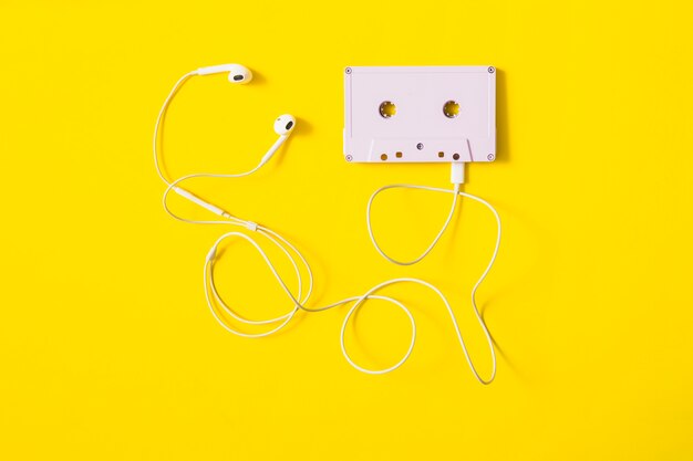 노란색 배경에 카세트 테이프에 연결된 흰색 귀 전화
