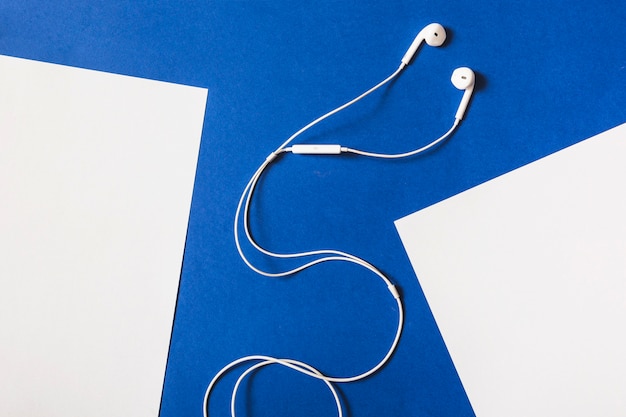 White earphone between the white paper on blue background