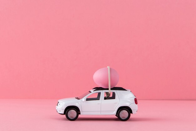 분홍색 계란과 배경이 있는 흰색 부활절 자동차