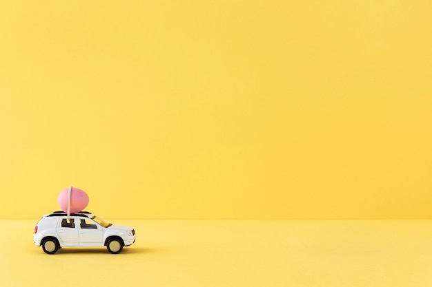 분홍색 달걀과 복사 공간이 있는 흰색 부활절 자동차