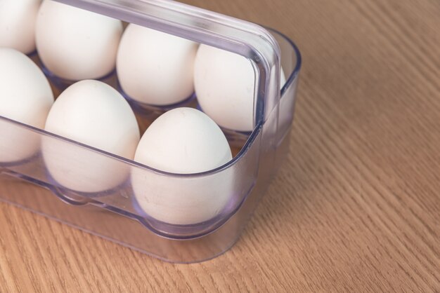 White egg carton on the brown wooden surface