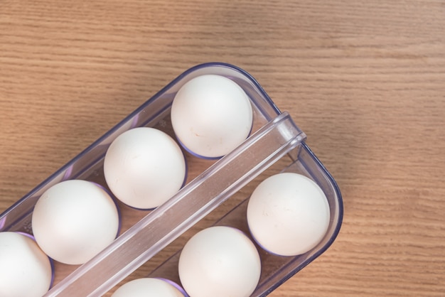 White egg carton on the brown wooden surface