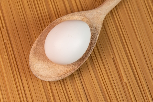 Free photo white egg and spoon on the raw pasta