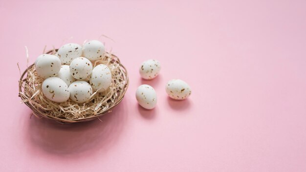 White eggs in nest on pink table