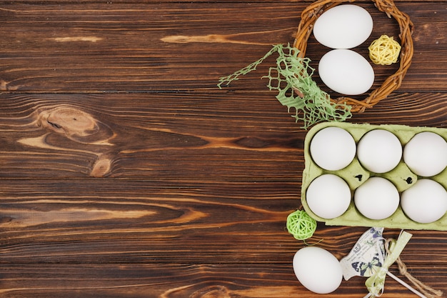 Белые яйца в стойку с птичкой и деревянными шариками на столе