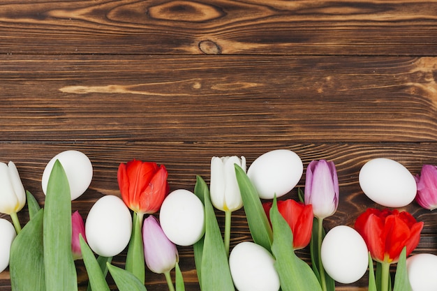 Foto gratuita uova bianche con tulipani sul tavolo