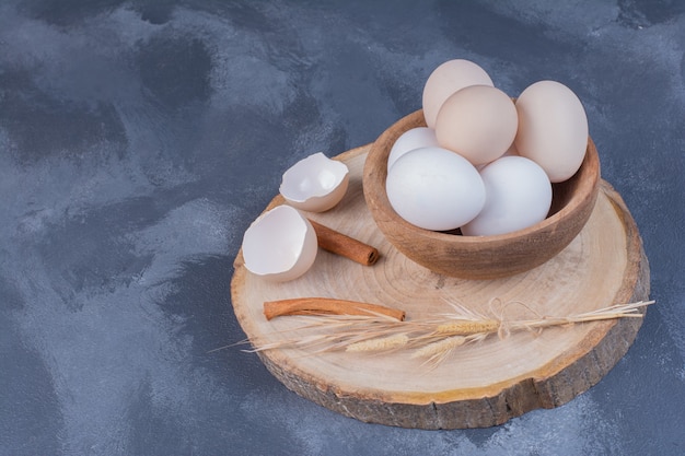 Free photo white eggs in a wooden cup on a wooden board