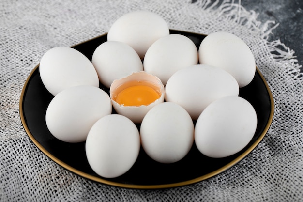 White eggs and yolk on black plate. 