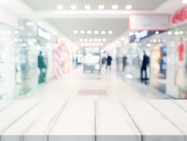 White empty desk in front of blur illuminated shopping center