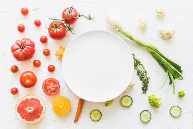 Белая пустая рамка над красочными овощами на текстурированном фоне