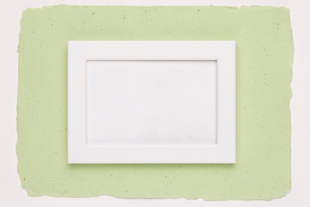 White empty frame on green paper background