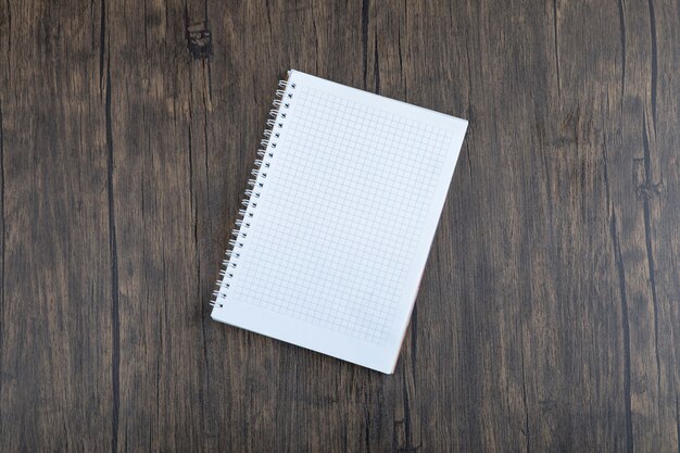 White empty sheet of paper placed on wooden table .