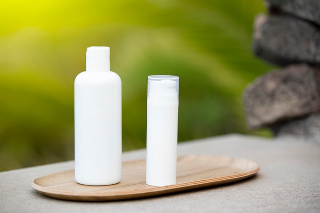 White empty tube of skincare bottle on bamboo plate