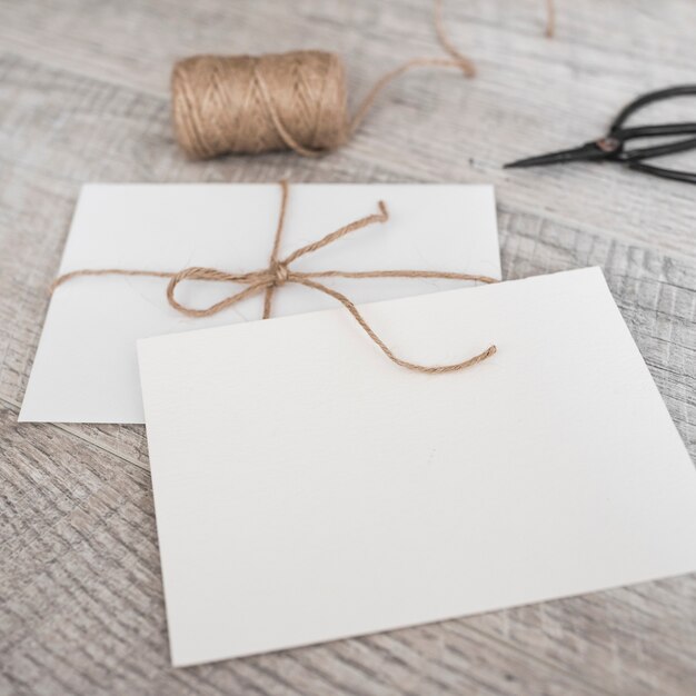 White envelopes with strings and scissor on wooden background