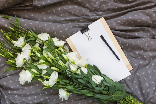 White eustoma bouquet; clipboard and pen on gray clothes